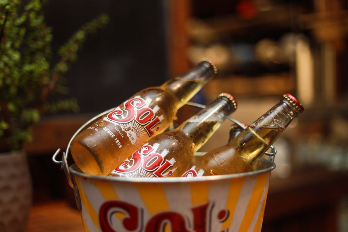 Garrafas de cerveja geladas dentro de um balde com gelo, ilustrando a conservação do frio em uma bolsa térmica